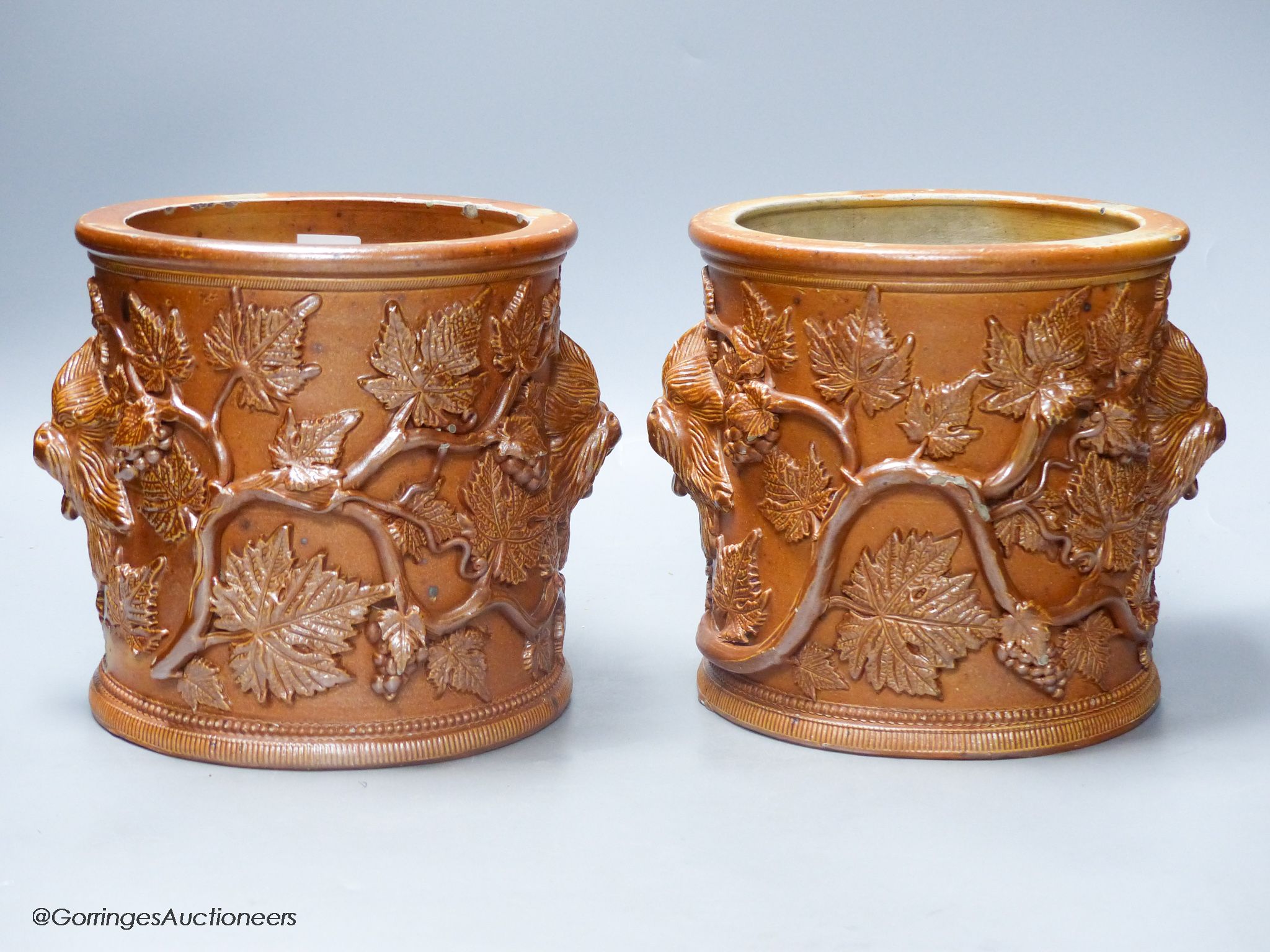 A pair of early 19th century salt glazed stoneware cylindrical pots, relief moulded with grapes and vine leaves